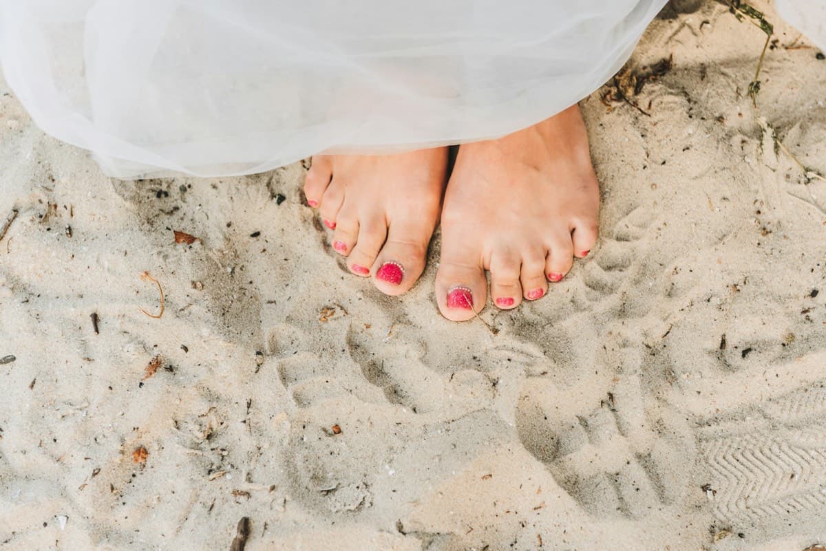 Pieds nus dans le sable, vernis rose